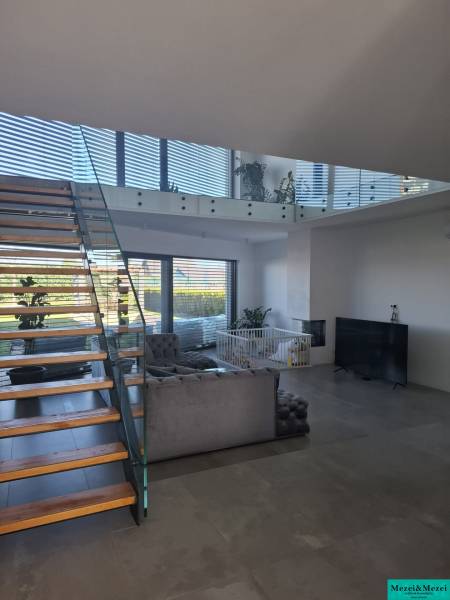 Moderný rodinný dom so záhradou, bazénom a nadštandardným priestorom - Obývacia izba v rodinnom dome so schodiskom a presklenými zábradliami.