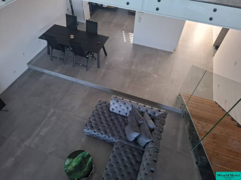 Moderný rodinný dom so záhradou, bazénom a nadštandardným priestorom - Interiér rodinného domu s pohľadom na jedálenský stôl, sedačku a schodisko.