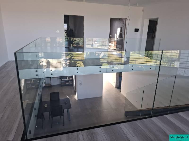 Moderný rodinný dom so záhradou, bazénom a nadštandardným priestorom - Interiér rodinného domu s preskleným zábradlím a podlahou s dreveným dekorom.