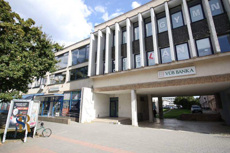 Prenájom centrum Galanty - Budova s kanceláriami a bankou v Galante, so stromom a chodníkom v popredí.
