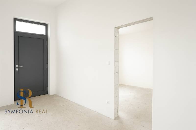 4-izbový rodinný dom Galanta – HODY - bez rezervačnej zálohy - Pohľad do interiéru rodinného domu s bielymi stenami a tmavými dverami.