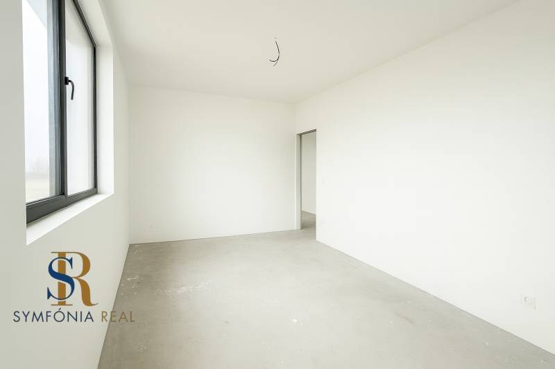 4-izbový rodinný dom Galanta – HODY - bez rezervačnej zálohy - Prázdna miestnosť s veľkým oknom, bielymi stenami a nedokončenou podlahou v rodinnom dome.