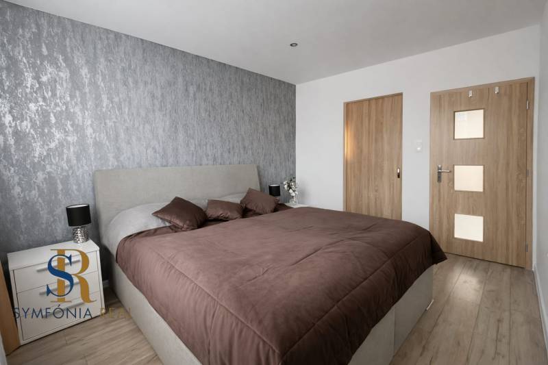 NOVINKA - Priestranných 74 m² v štýlovo zariadenom byte - Spálňa v 3-izbovom byte s posteľou a stenou s textúrovaným dekorom, podlaha s dreveným dekorom.