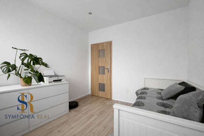 NOVINKA - Priestranných 74 m² v štýlovo zariadenom byte - Svetlá spálňa v 3-izbovom byte s bielym nábytkom a podlahou s dreveným dekorom.