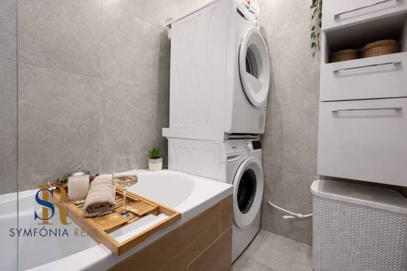 NOVINKA - Priestranných 74 m² v štýlovo zariadenom byte - Kúpeľňa s vaňou, práčkou a sušičkou v 3-izbovom byte. Na vani je pohár vína.