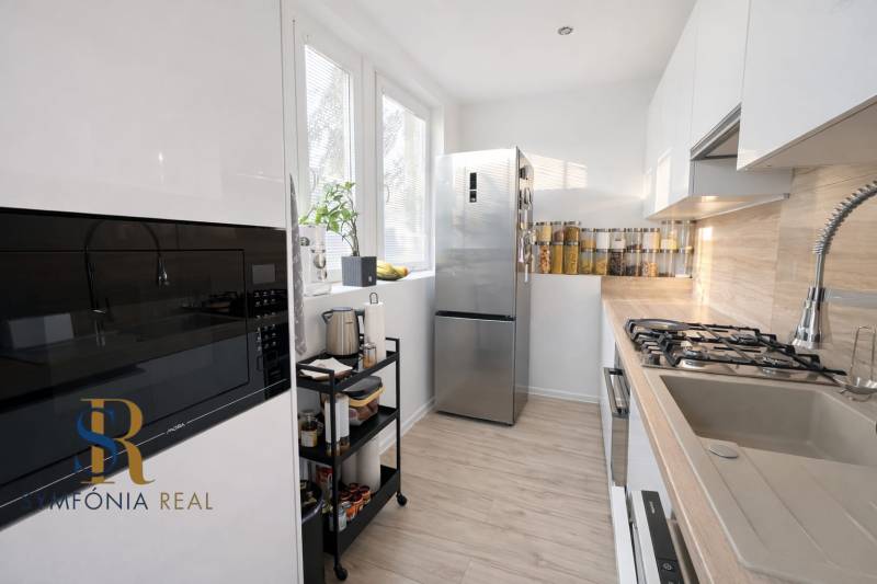 NOVINKA - Priestranných 74 m² v štýlovo zariadenom byte - Kuchyňa v 3-izbovom byte s podlahou s dreveným dekorom a modernými spotrebičmi.