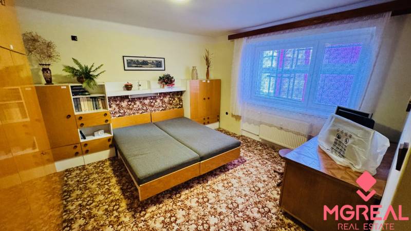 Na predaj 3 i  byt s loggiou aj terasou - Prievidza 75,24 m2 - Izba v 3-izbovom byte s dreveným dekorom nábytku a kobercom na podlahe.