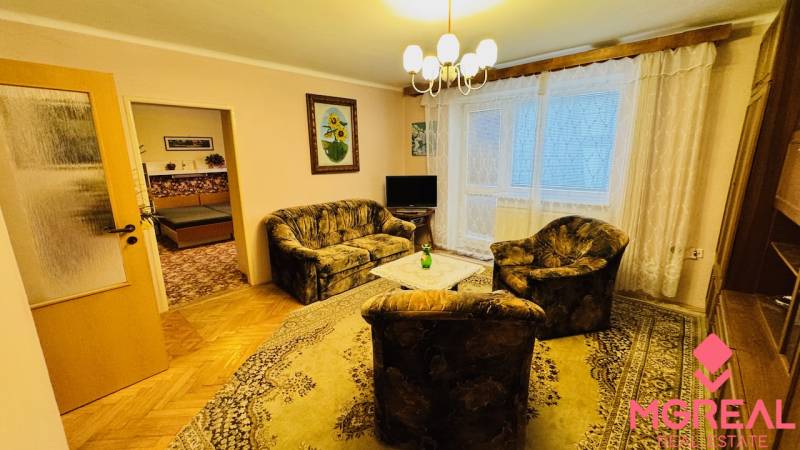 Na predaj 3 i  byt s loggiou aj terasou - Prievidza 75,24 m2 - Obývacia izba v 3-izbovom byte s pohovkou, kreslom a podlahou s dreveným dekorom.