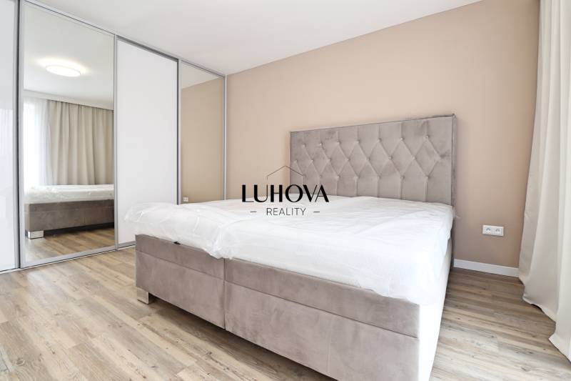 Na PRENÁJOM_v NOVOSTAVBE krásny 3-izbový byt s parkovacím státím - Spálňa v 3-izbovom byte s pohodlnou posteľou, vstavanou skriňou a podlahou s dreveným dekorom.