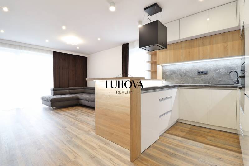 Na PRENÁJOM_v NOVOSTAVBE krásny 3-izbový byt s parkovacím státím - Interiér 3-izbového bytu s kuchyňou, sedačkou a podlahou s dreveným dekorom.