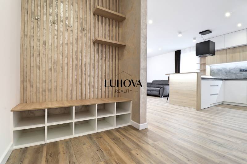 Na PRENÁJOM_v NOVOSTAVBE krásny 3-izbový byt s parkovacím státím - Interiér 3-izbového bytu s podlahou s dreveným dekorom, kuchyňou a obývacou časťou.