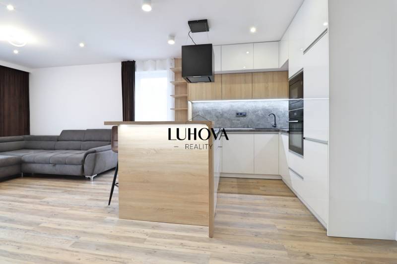 Na PRENÁJOM_v NOVOSTAVBE krásny 3-izbový byt s parkovacím státím - Obývačka s kuchyňou a podlahou s dreveným dekorom v 3-izbovom byte.