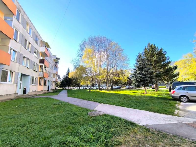 ‼️ PARTIZÁNSKE - 3,5 IZBOVÝ BYT NA PREDAJ, VEĽKÁ OKRUŽNÁ ‼️ - Bytový dom na Veľkej Okružnej v Partizánskom, pred ktorým rastú stromy a parkujú autá.