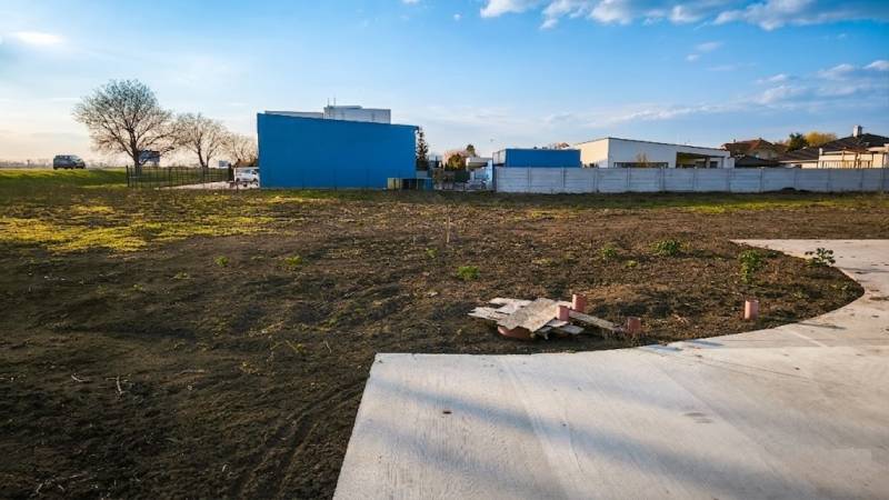 I Na predaj komerčný stavebný pozemok – Kráľová nad Váhom - Pozemky - komerčné v Kráľovej nad Váhom, asfaltová plocha, budova a zeleň.