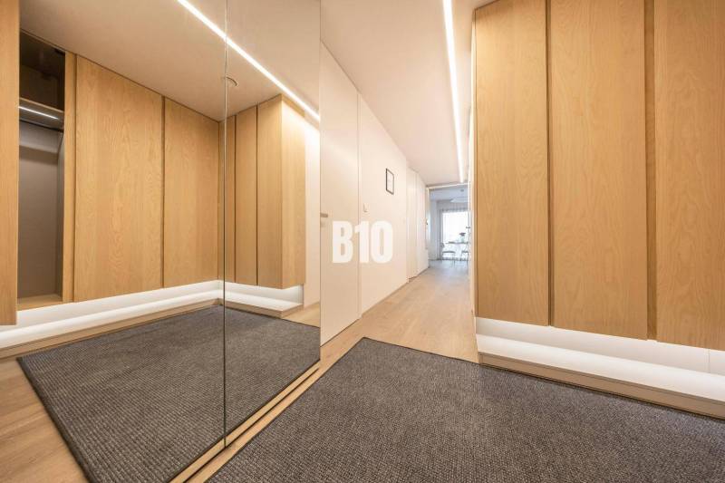 LUXUSNÝ 3-IZBOVÝ BYT NA MIERU V NADČASOVEJ NOVOSTAVBE NA ZAČIATKU KOLI - Chodba v 3-izbovom byte s podlahou s dreveným dekorom a zrkadlom.