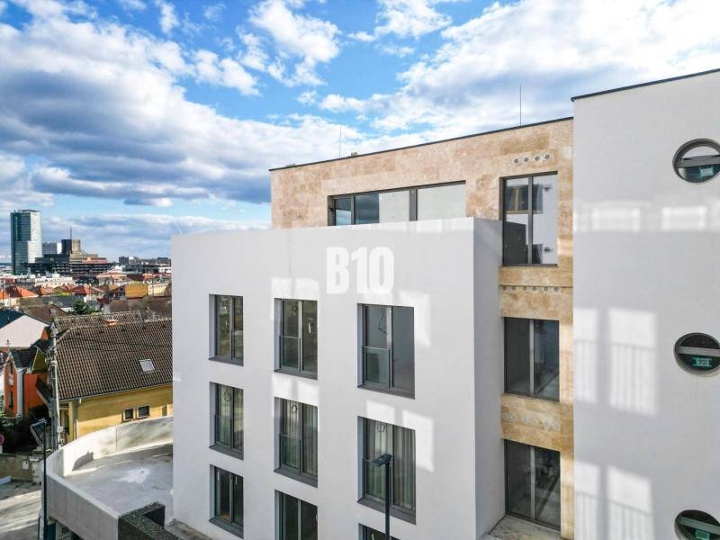 LUXUSNÝ 3-IZBOVÝ BYT NA MIERU V NADČASOVEJ NOVOSTAVBE NA ZAČIATKU KOLI - Biela budova s veľkými oknami v Bratislave III na Matúškovej so 3-izbovým bytom.