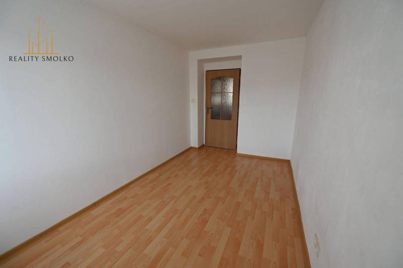 EXKLUZÍVNE: Priestranný 2-izbový byt s vlastnou malou záhradkou v srdc - Izba v 2-izbovom byte s podlahou s dreveným dekorom a bielymi stenami.