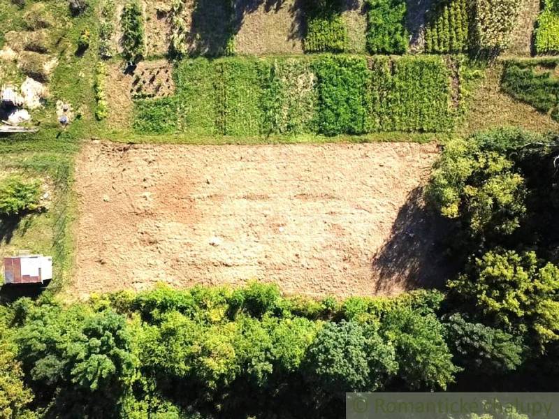 Stavebný pozemok pri Nitre so stavebným povolením v tichej lokalite - Pozemky - bývanie v Hosťovej, lúka s okolitými zelenými parcelami viditeľnými z výšky.