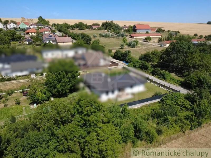 Stavebný pozemok pri Nitre so stavebným povolením v tichej lokalite - Panoramatický pohľad na pozemky - bývanie v obci Hosťová obklopené zeleňou a domami.