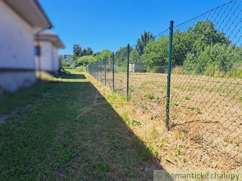 Stavebný pozemok pri Nitre so stavebným povolením v tichej lokalite - Trávnatý pozemok s plotom v Hosťovej, ideálny na bývanie.