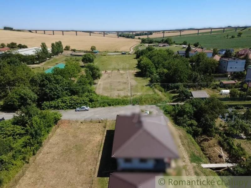 Stavebný pozemok pri Nitre so stavebným povolením v tichej lokalite - Hosťová zobrazuje vidiecke pozemky na bývanie s panorámou mosta v pozadí.