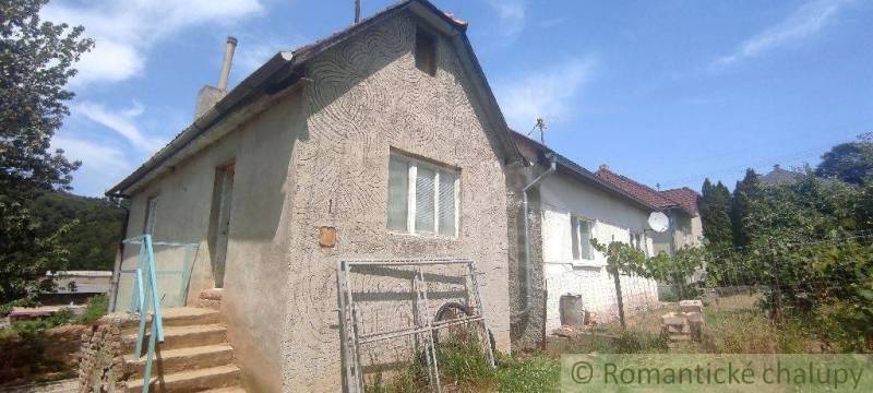 CENA DOHODOU Menší domček v príjemnom prostredí obce Šiatorská Bukovin - Rodinný dom v Šiatorskej Bukovinke s kamennými schodmi a záhradou, na pozadí je modrá obloha.
