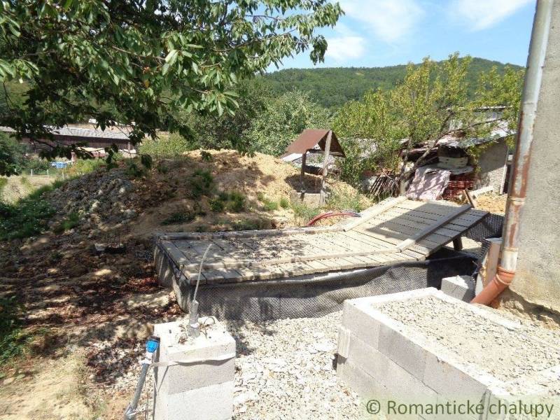 CENA DOHODOU Menší domček v príjemnom prostredí obce Šiatorská Bukovin - Zadný dvor rodinného domu v Šiatorskej Bukovinke s kopou zeme a stromami.