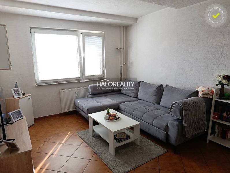 Prenájom, dvojizbový byt Nováky - Obývacia izba 2-izbového bytu s rohovou sedačkou a stolíkom na podlahe s dreveným dekorom.