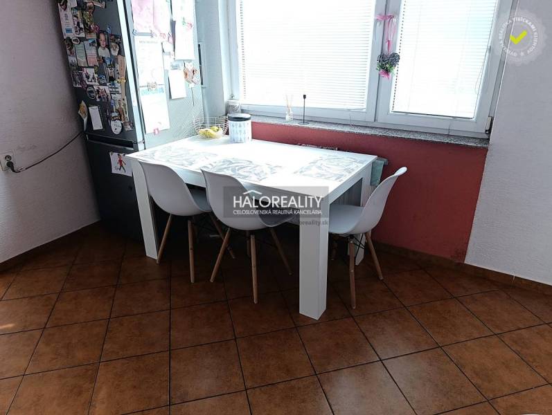 Prenájom, dvojizbový byt Nováky - Kuchyňa 2-izbového bytu s jedálenským stolom, bielymi stoličkami a oknom.