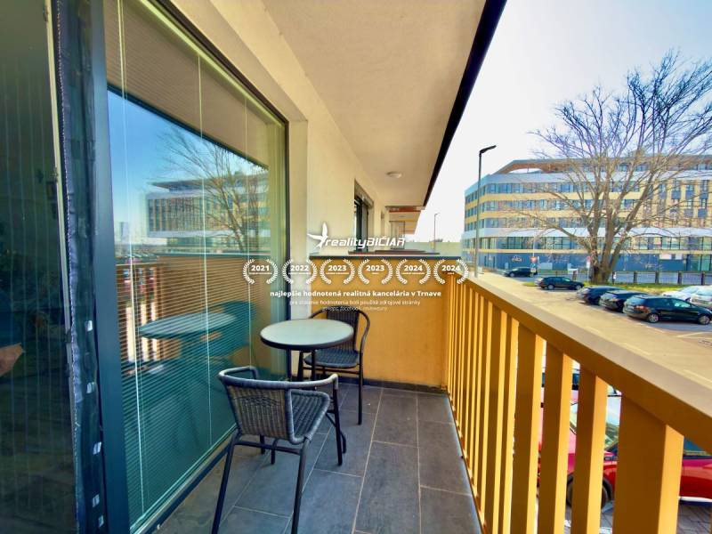 Na predaj moderný 2 izbový byt, komplex MIKO Trnava - Balkón 2-izbového bytu na Mikovíniho ulici v Trnave s posedením a výhľadom na ulicu.