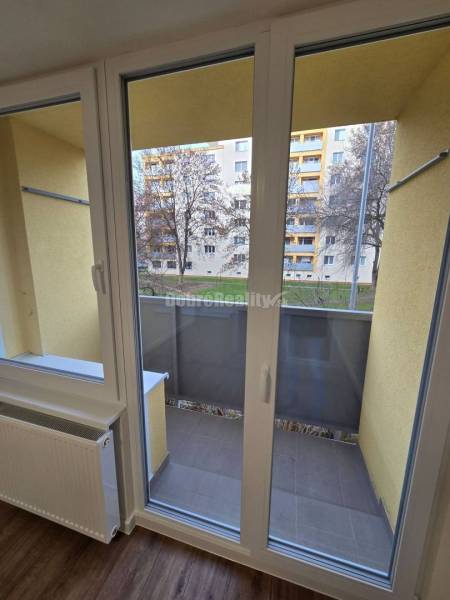3 izbový byt na Starom Sídlisku o výmere 74m2. - Francúzske okno v 3-izbovom byte s podlahou s dreveným dekorom a výhľadom na balkón.
