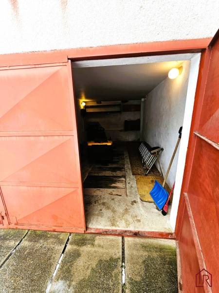 Predaj 5-izbový dom v Kameňanoch, okres Revúca - Garáž v rodinnom dome v Kameňanoch s otvorenými kovovými dverami a náradím.