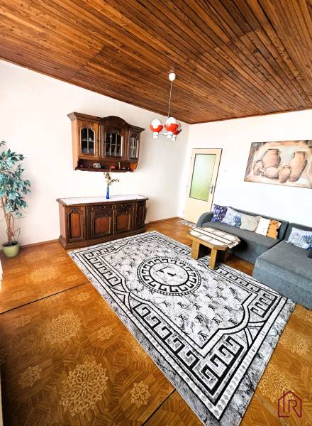 Predaj 5-izbový dom v Kameňanoch, okres Revúca - Obývacia izba v rodinnom dome s podlahou s dreveným dekorom a sedacou súpravou.
