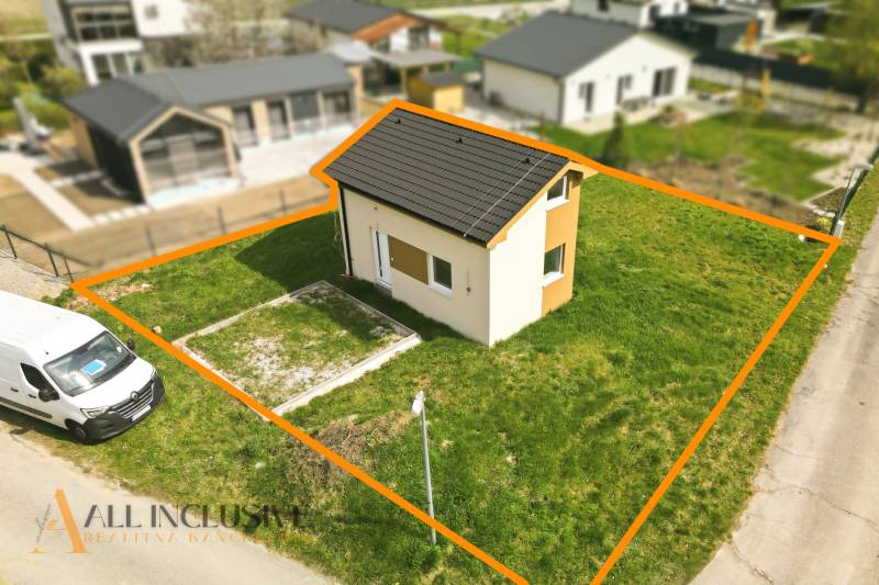 Na predaj rekreačný dom pri jazere, Vojka nad Dunajom - Chata vo Vojke nad Dunajom s vyhradeným pozemkom, vedľa zaparkovanej dodávky.