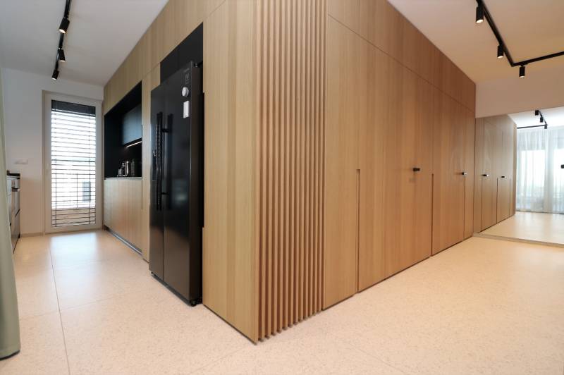 NUERA︱Penthouse s terasou s krásnymi výhľadmi v Dúbravke - Kuchyňa v 4-izbovom byte s dekorom dreva, čiernou chladničkou a bielymi dlaždicami.