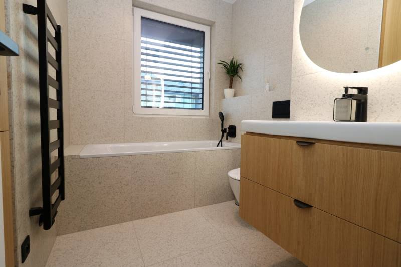 NUERA︱Penthouse s terasou s krásnymi výhľadmi v Dúbravke - Kúpeľňa v 4-izbovom byte s vaňou, umývadlom a dreveným dekorom skrinky.