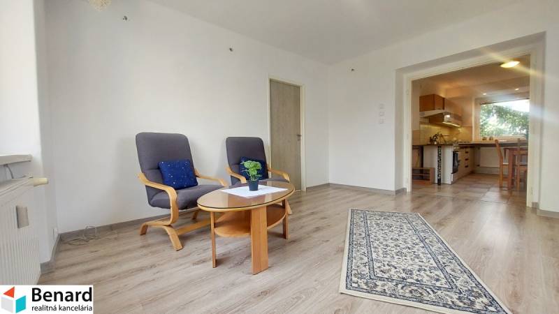 Na PRENÁJOM, VEĽKÝ 2 izb. TEHLOVÝ BYT, SÍDLISKO II., PREŠOV  - Obývacia izba v 2-izbovom byte s podlahou s dreveným dekorom a pohodlnými kreslami.