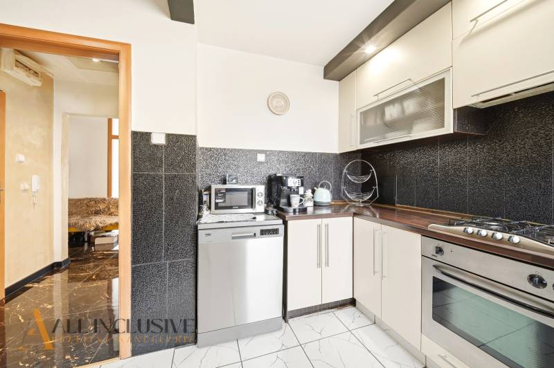 Na predaj 4-izb. byt s loggiou , Dunajská Streda - Kuchyňa v 4-izbovom byte s čiernymi obkladmi a spotrebičmi, podlaha s dreveným dekorom.