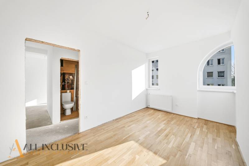 Na predaj zrekonštr. 3-izb. byt s balkónom, Dun.Streda - Prázdna miestnosť s radiátorom a podlahou s dreveným dekorom v 3-izbovom byte.