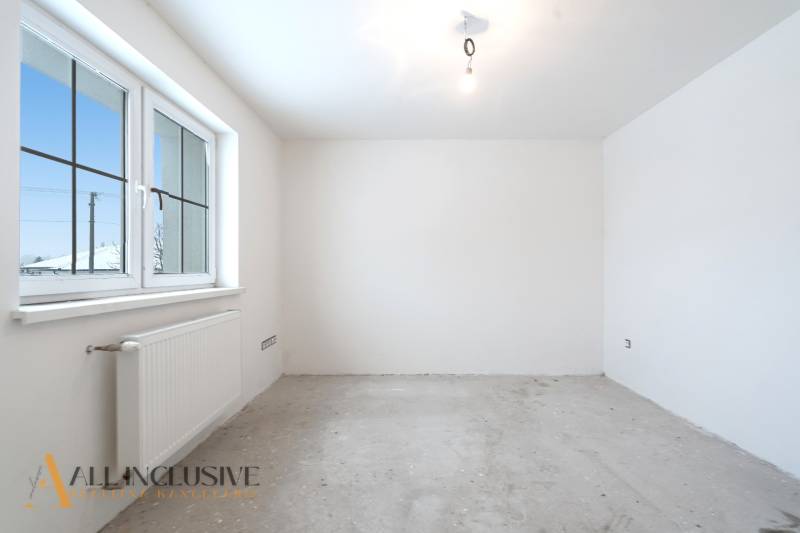 Na predaj poschodový 6-izbový rodinný dom, Horné Mýto - Prázdna izba v rodinnom dome s betónovou podlahou a veľkým oknom.