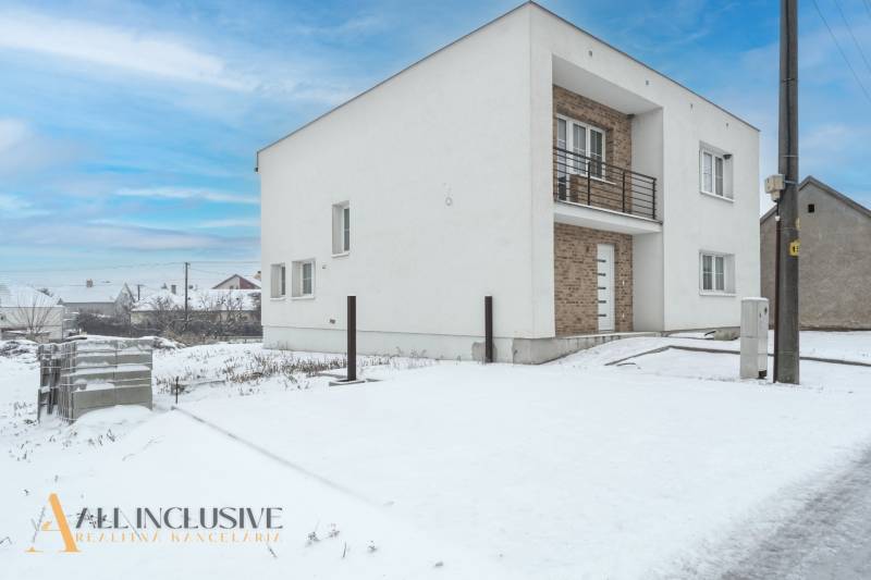 Na predaj poschodový 6-izbový rodinný dom, Horné Mýto - Rodinný dom v Hornom Mýte pokrytý snehom s tehlovým vstupom a balkónom.