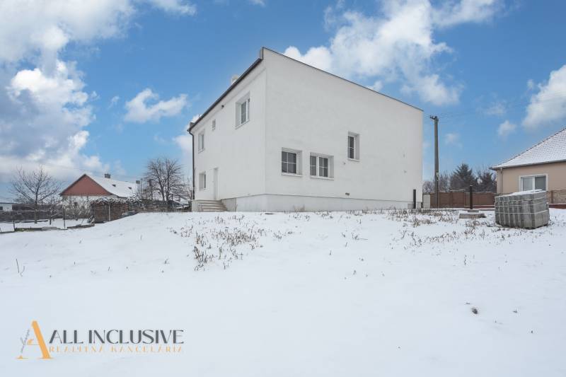 Na predaj poschodový 6-izbový rodinný dom, Horné Mýto - Rodinný dom v Hornom Mýte zasnežený počas zimy s modrou oblohou.