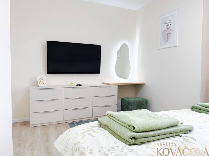 Na predaj 3 izbový byt s terasou, Trenčín, ul. Saratovská - Spálňa s televízorom, zrkadlom a komodou v 3-izbovom byte, podlaha s dreveným dekorom.