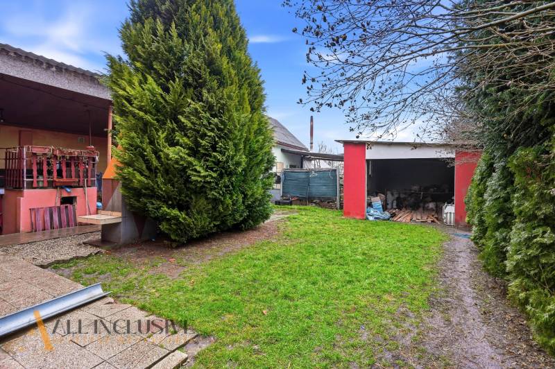 Na predaj 4-izb. rodinný dom s garážou, Okoč - Záhrada rodinného domu na ulici Okoč v meste Veľký Meder, s červenou garážou.