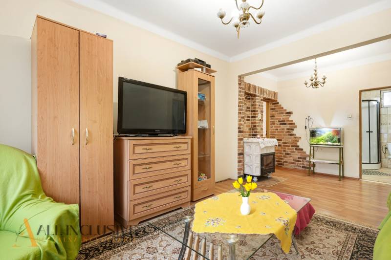 Na predaj 4-izb. rodinný dom s garážou, Okoč - Obývacia izba v rodinnom dome s tehlovými detailmi a podlahou s dreveným dekorom.