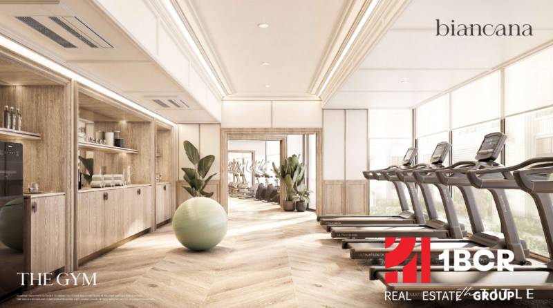 BIANCANA PHUKET - Interiér posilňovne s podlahou s dreveným dekorom a moderným fitness vybavením. Výstavba bytov.