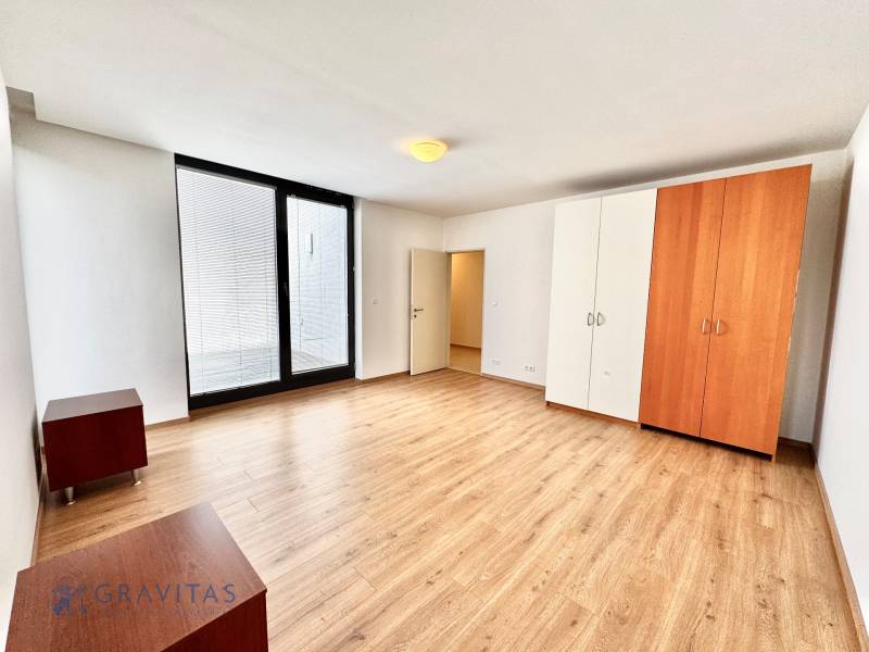 Na predaj veľký 2-izbový byt s terasou a wellness - Koliba - Priestranná izba so skriňou a drevenou podlahou v 2-izbovom byte.