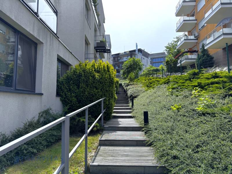 Na predaj veľký 2-izbový byt s terasou a wellness - Koliba - Schody vedú popri moderných budovách a zeleni na ulici Tupého v Bratislave.