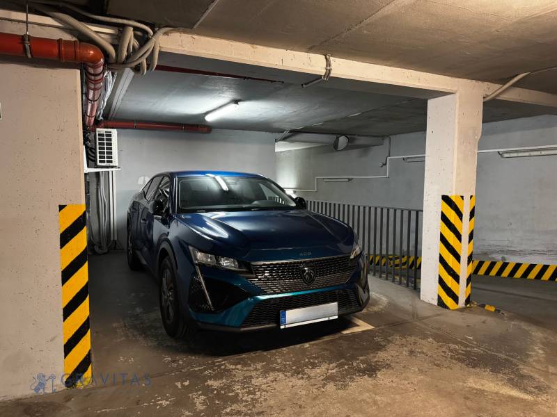 Na predaj veľký 2-izbový byt s terasou a wellness - Koliba - Zaparkované auto v podzemnej garáži s bezpečnostnými pruhmi a osvetlením.