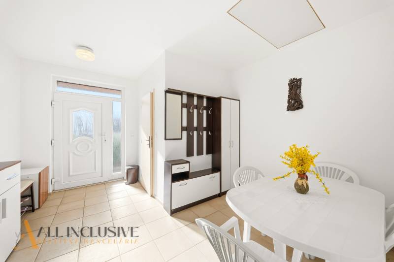 Na predaj 4-izb. rodinný dom s garážou, Kútniky - Interiér rodinného domu s bielym stolom, plastovými stoličkami a vešiakovou stenou.